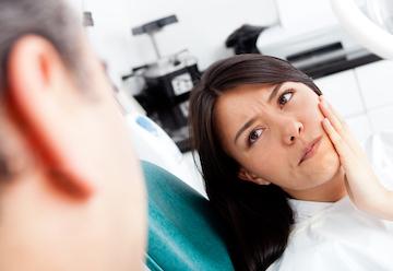 Woman holding face in pain at emergency dentist in Arlington WA