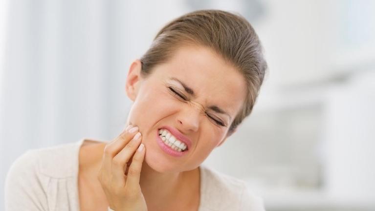 woman holding jaw in pain